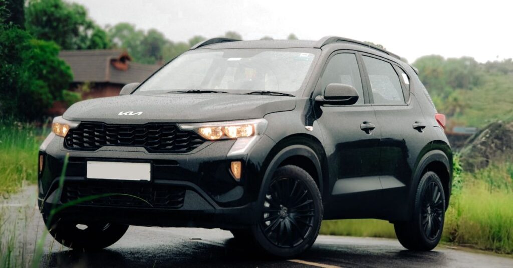 Black Kia Sonet SUV parked on a quiet road, featuring LED headlights, black alloy wheels, and a modern compact crossover design.