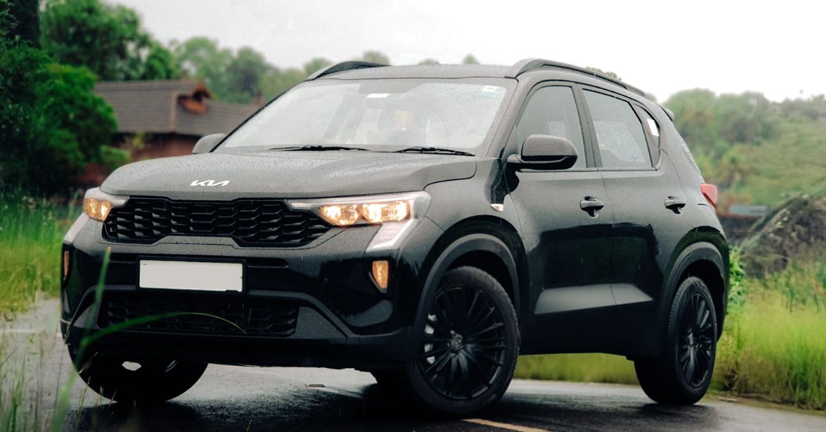 Black Kia Sonet SUV parked on a quiet road, featuring LED headlights, black alloy wheels, and a modern compact crossover design.