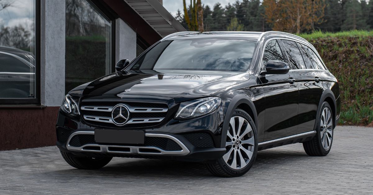 Black Mercedes-Benz E-Class All-Terrain wagon parked outside a modern building, featuring premium styling, alloy wheels, and a rugged luxury design.