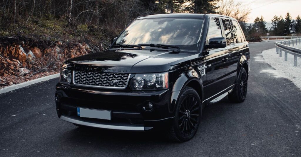 Black Range Rover Sport SUV parked on a scenic mountain road, featuring a premium grille, black alloy wheels, and luxury styling.