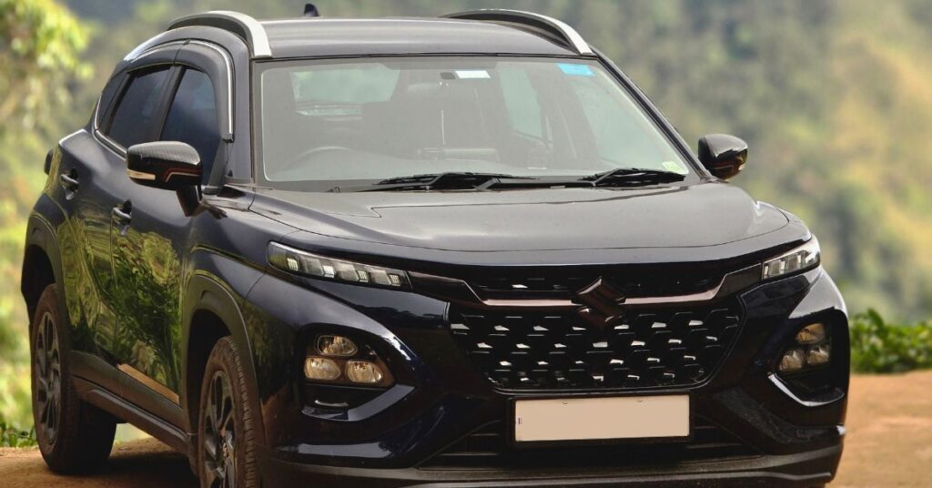 Black Suzuki SUV parked with a mountain backdrop, featuring modern styling, LED lighting, roof rails, and a bold grille.