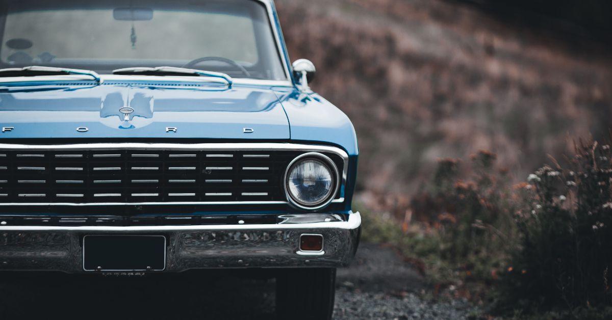 Front view of a classic blue Ford pickup truck parked outdoors, highlighting its vintage grille, round headlights, and timeless design.
