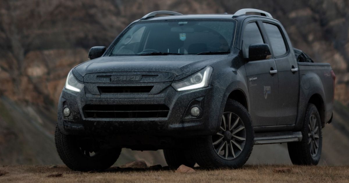 Gray Isuzu D-Max pickup truck parked in a rugged mountain landscape, featuring off-road styling, LED headlights, and a durable design.