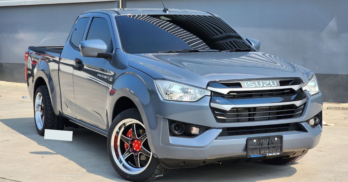 Gray Isuzu D-Max Spacecab pickup truck parked outdoors, featuring a bold grille, custom alloy wheels, tinted windows, and rugged styling.