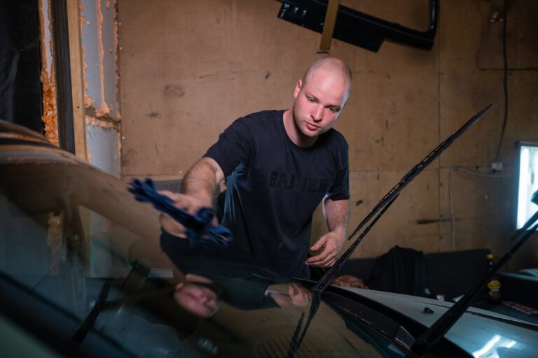A Man Wiping a Car Windshield.