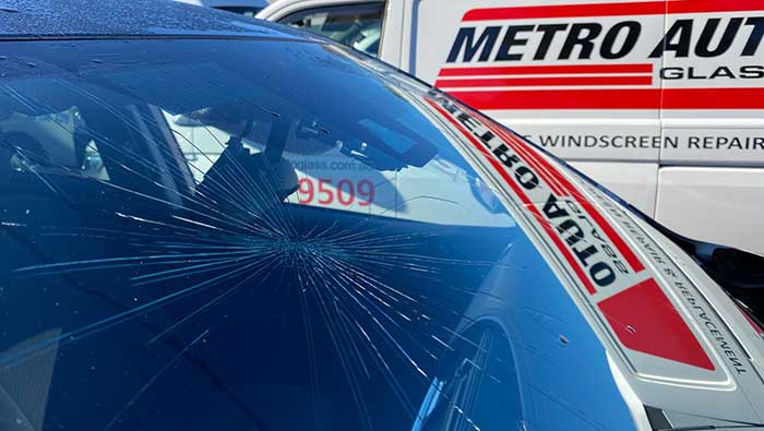 Cracked windscreen glass with Metro Auto Glass van in background