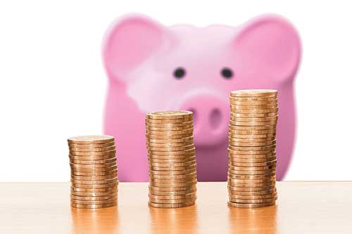 Stacks of coins in front of piggy bank