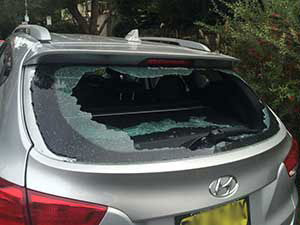 Red hatchback window from the outside showing broken glass